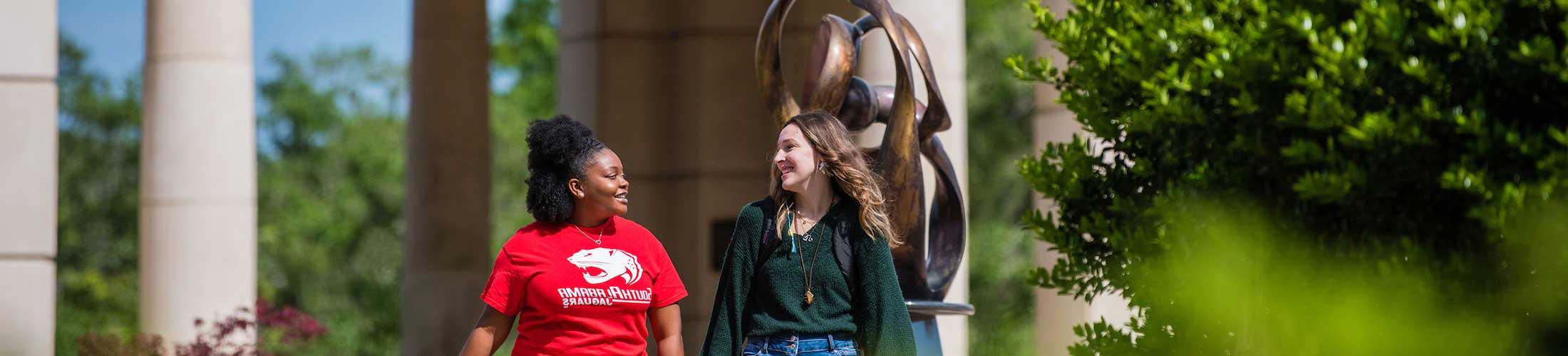 Two students talking and walking outside of Moulton Tower on campus.